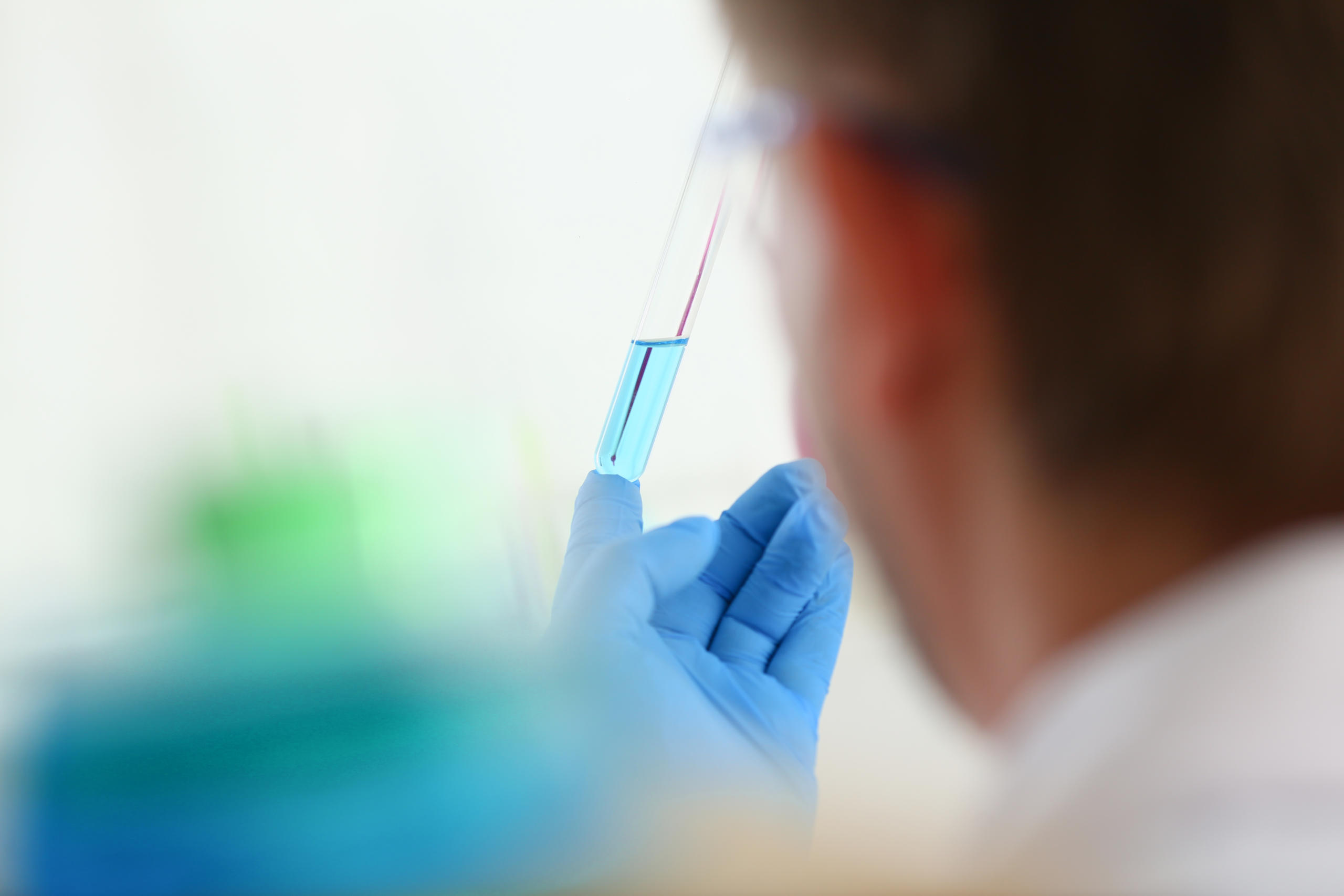 A scientist holds a glass test tube in his hand.