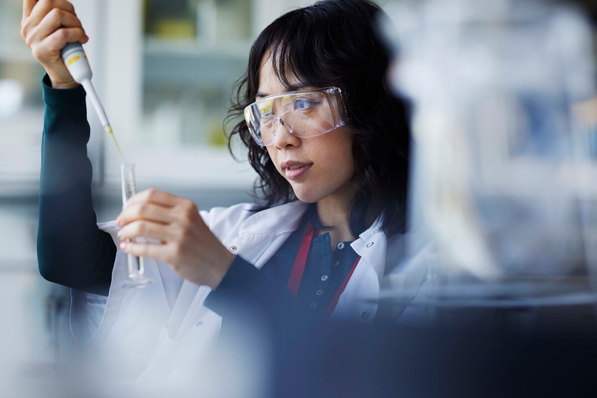 A female scientist examines the contents of a test tube in her lab.