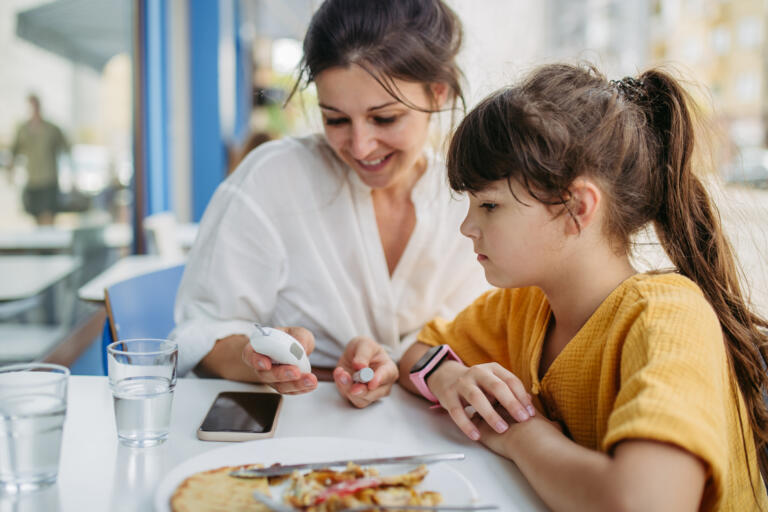 Girl with type 1 diabetes checking her blood sugar before eating.