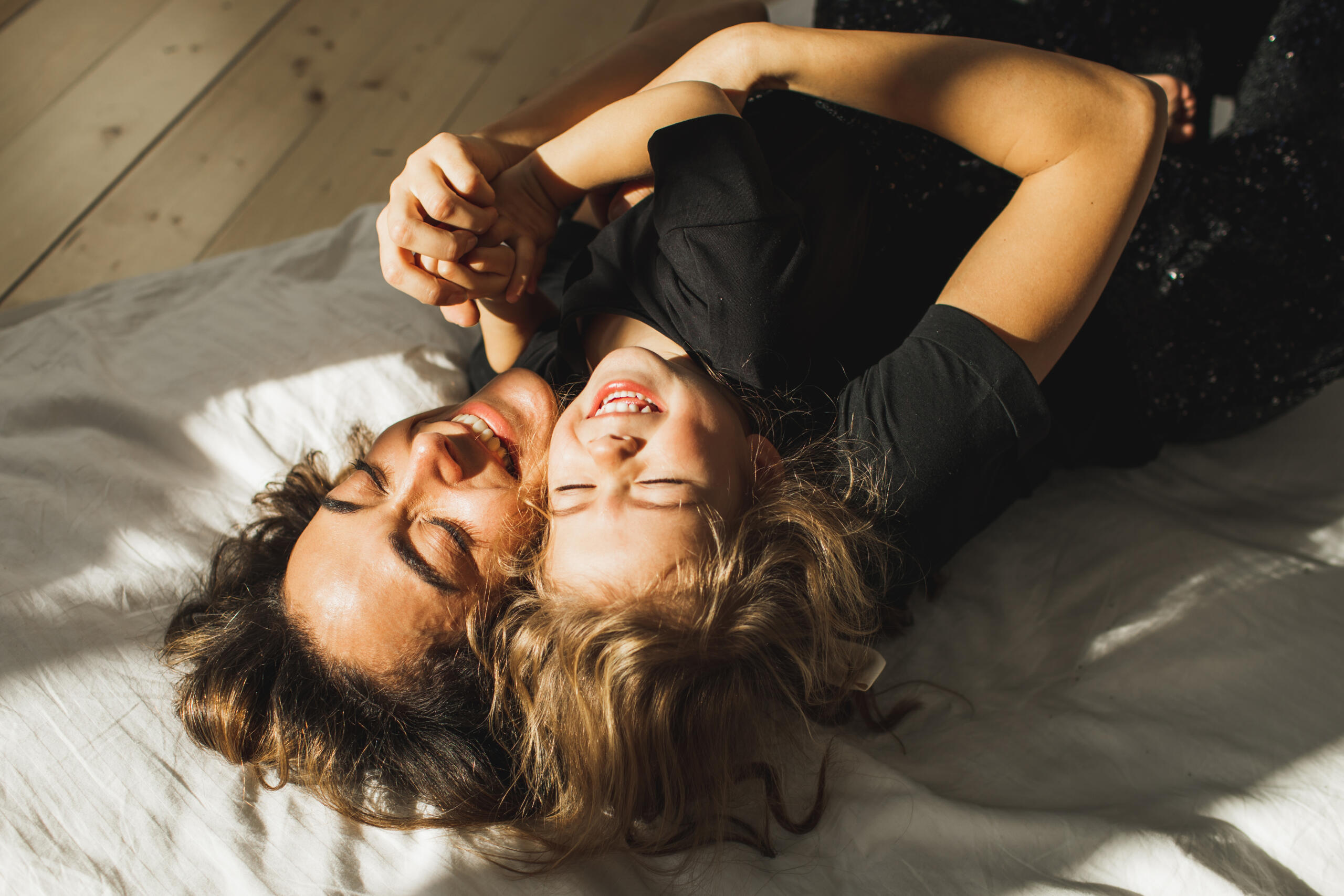 Happy mother and daughter having fun and playing together on the bed at home.