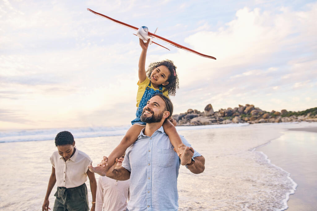 Diviértete en familia, paseando o en avión en la playa al atardecer, en el océano o en el mar en vacaciones en libertad, creando vínculos energéticos o jugando. Sonríe, feliz o niños con juguetes voladores, a caballito o padres interraciales por el agua