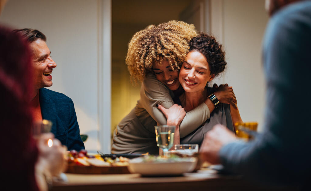 Friends hug at a holiday dinner